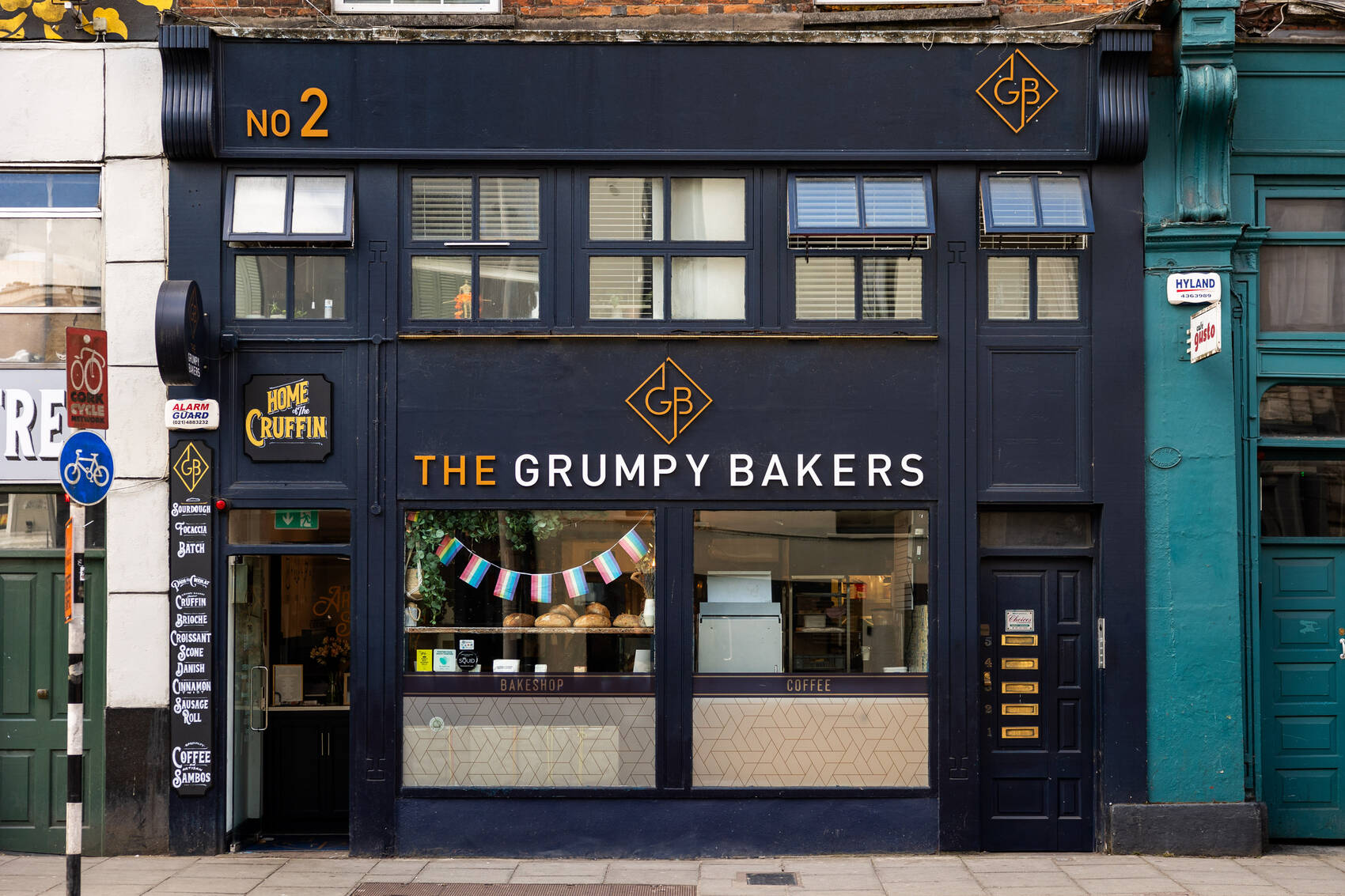 The navy shopfront of The Grumpy Bakers at 2 Washington St, Cork, with bunting in the window and the GB monogram on the fascia.